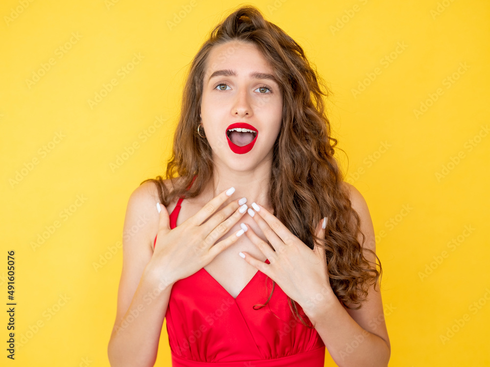 Excited woman. Happy surprise. Unbelievable emotion. Elegant pretty amazed lady in red dress and lipstick curly hair posing isolated yellow.
