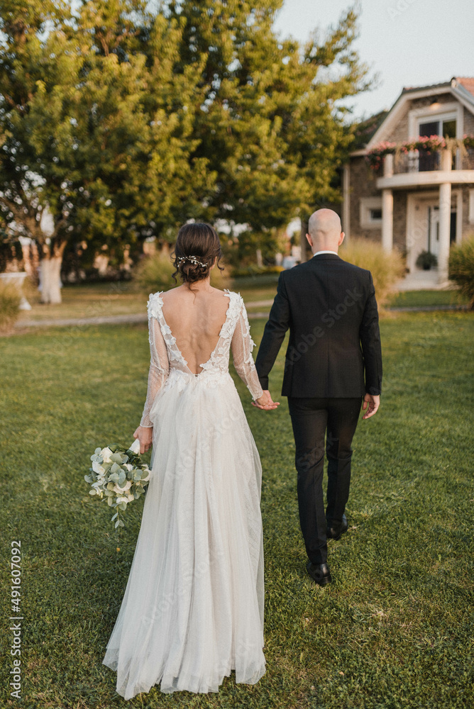 Newlywed romantic wedding couple walking. The bride and groom walk holding hands.