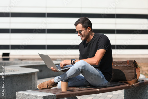 Handsome man using laptop o...