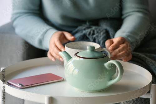 Woman with cup of tasty blue tea at table, closeup