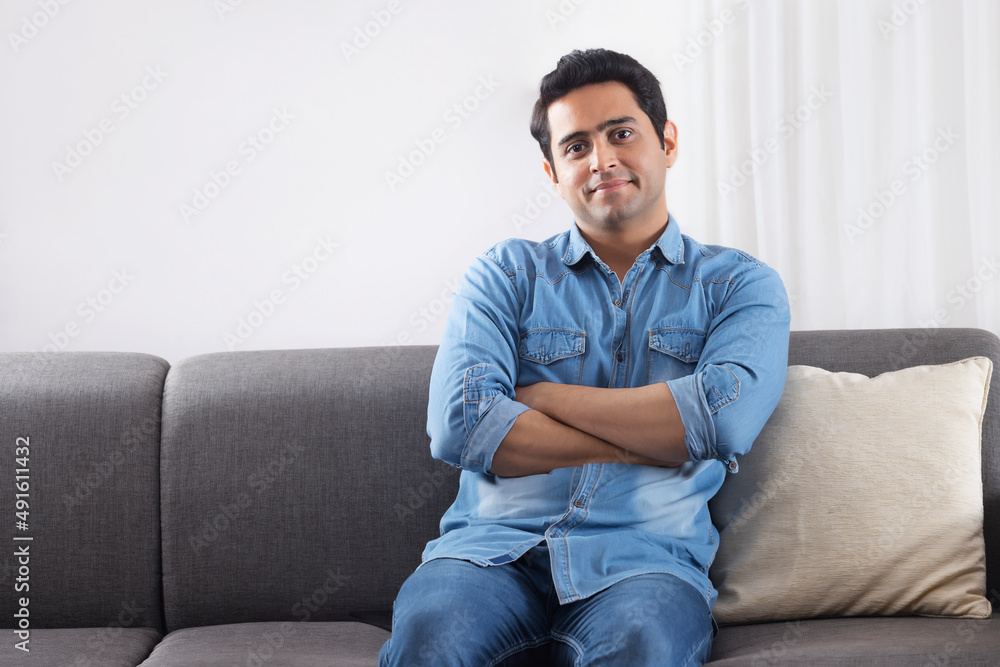 Man looking at camera while relaxing on sofa at home Man looking at camera while relaxing on sofa at home