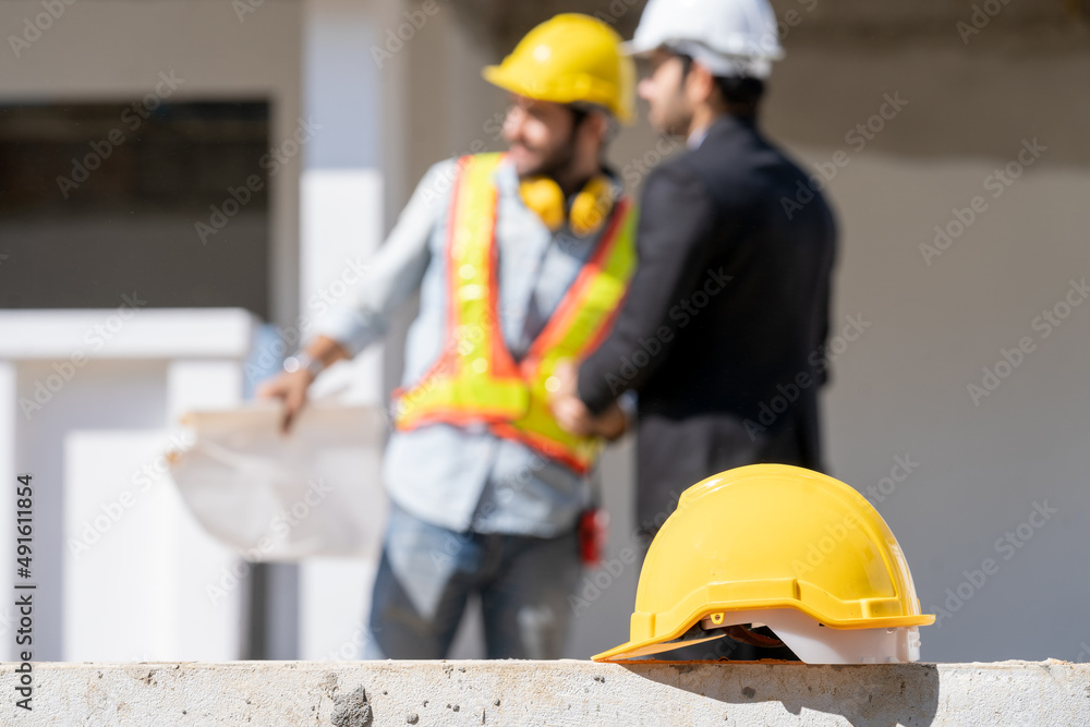 Helmet in construction site and and Engineer with businessman background,Safety helmets for workplace construction or industrial use to prevent accidents and hard hats. Helmet in construction site and and Engineer with businessman background,Safety helmets for workplace construction or industrial use to prevent accidents and hard hats.