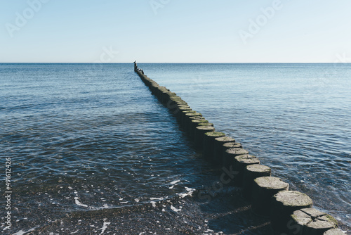 wooden breakwater in calm baltic sea against blue sky