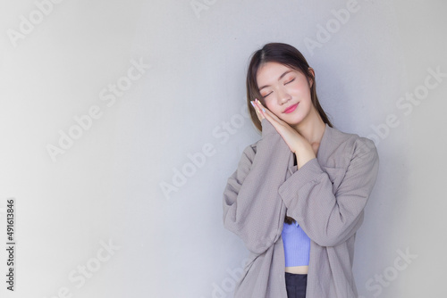 Smiling beautiful Asian woman poses for a good night nap on white background.