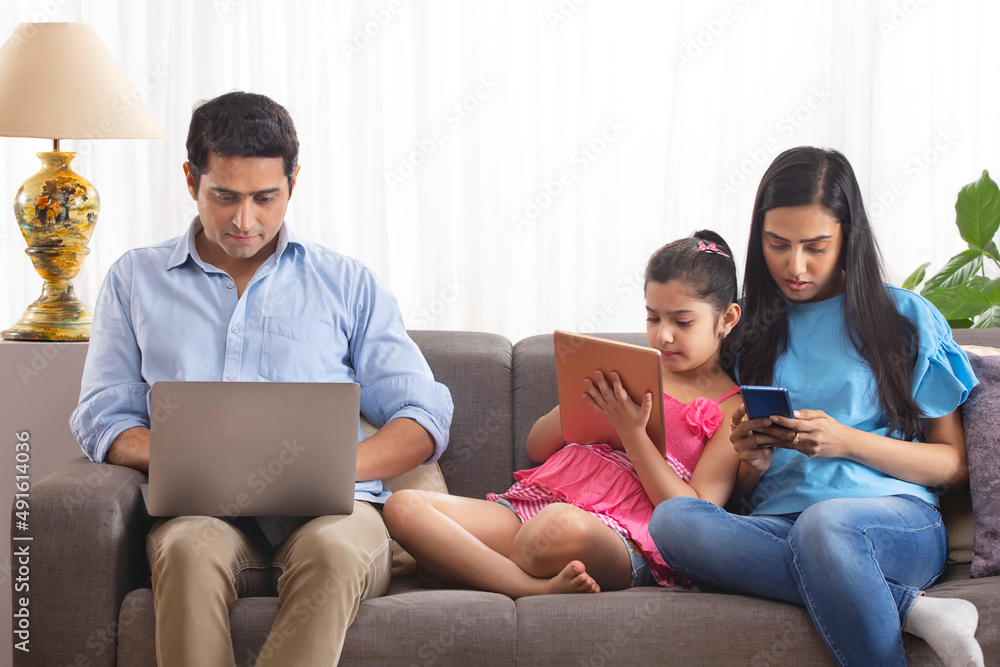 Family members using gadgets in living room Family members using gadgets in living room