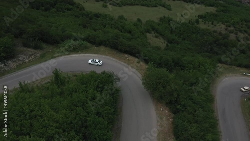 a car drives along a mountain road from a drone