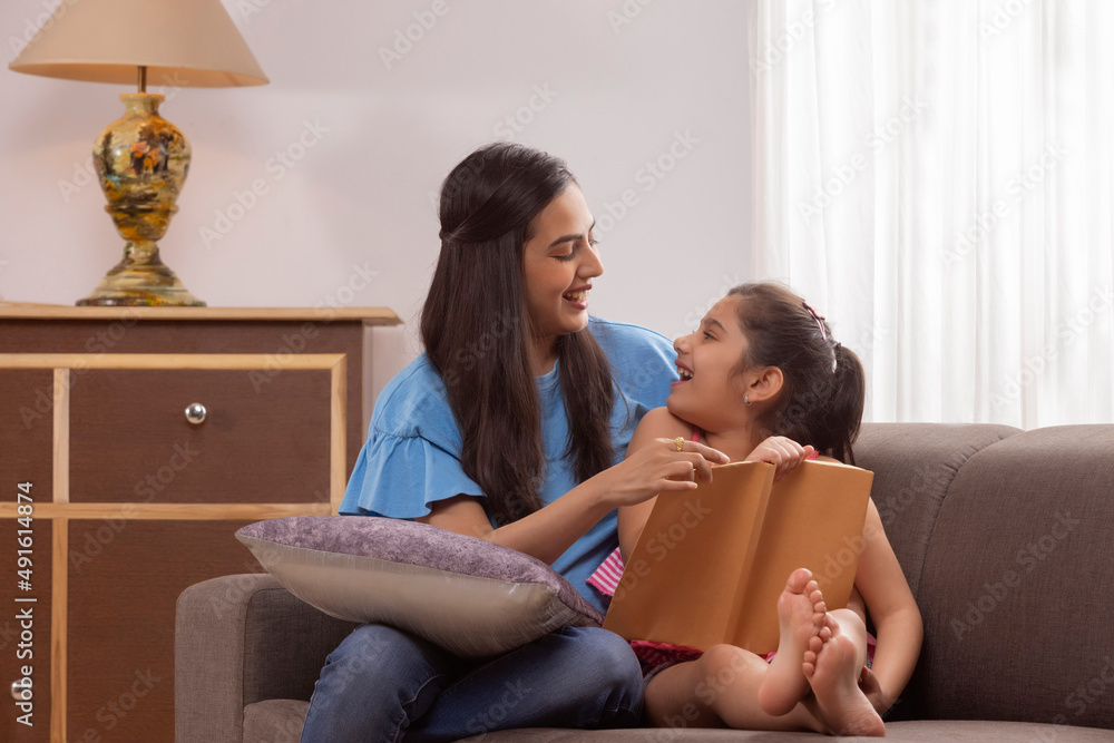 Mother helping her little daughter while reading book Mother helping her little daughter while reading book