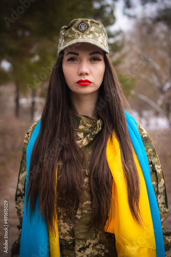 a young girl in military uniform holds a gun in her hands, on her shoulders the flag of Ukraine, aims and shoots, the army defends Ukraine, weapons machine gun, salutes in uniform  photo