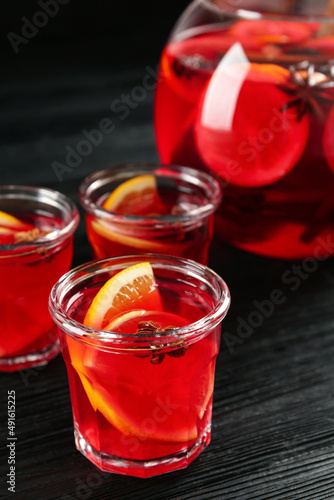 Bowl and glasses of delicious aromatic punch drink on black wooden table
