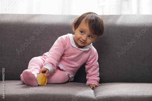 Portrait of a cute baby sitting on sofa and looking elsewhere photo