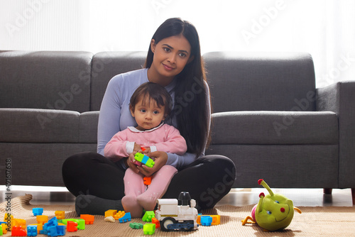 Mother playing with her baby in living room with toys photo