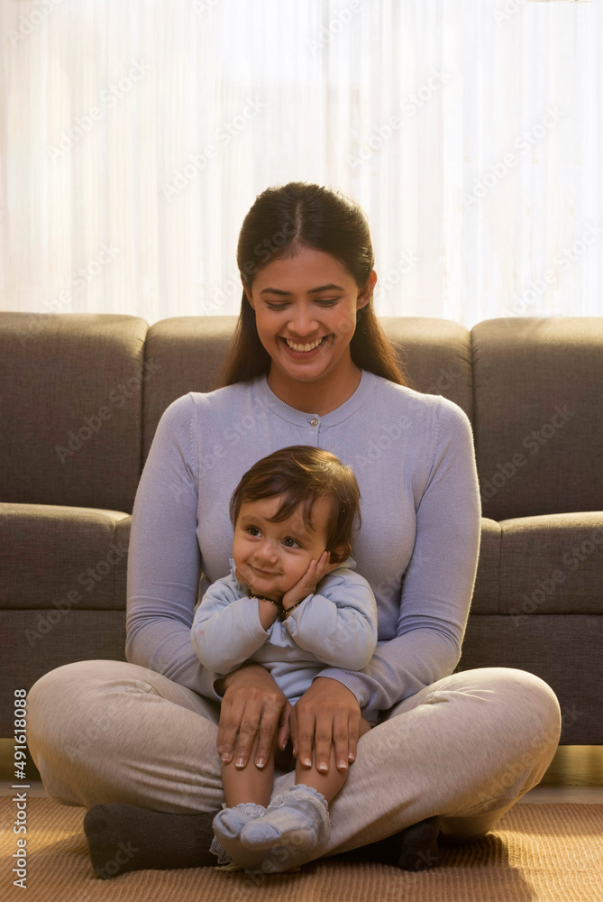 Cute kid sitting on mother's lap with hands on cheek and looking away Cute kid sitting on mother's lap with hands on cheek and looking away