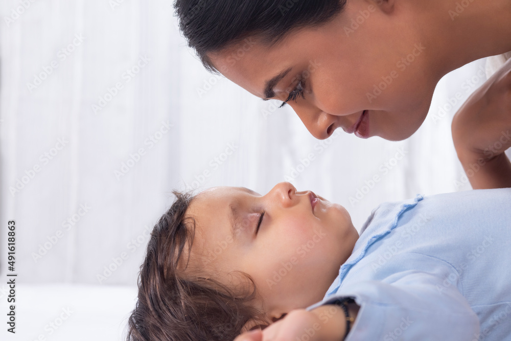 Portrait of mother looking at sleeping baby with affection Portrait of mother looking at sleeping baby with affection