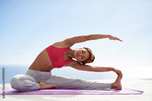 Attaining full body balance. Shot of a young woman practicing yoga outside on a sunny day.