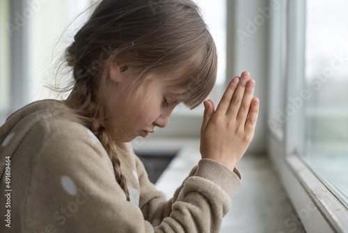 Tableau sur toile Praying little girl near window
