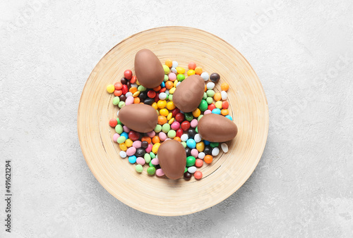 Plate with chocolate Easter eggs and candies on light background © Pixel-Shot