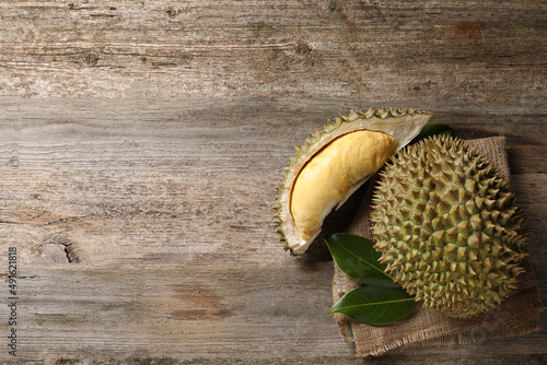 Fresh ripe durian fruits on wooden table, flat lay. Space for text