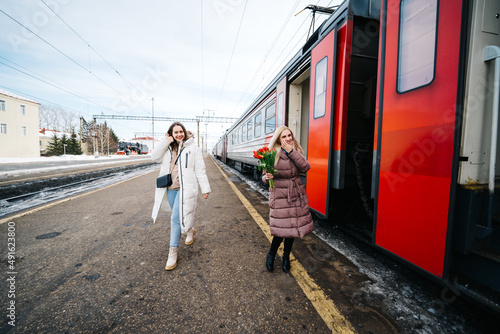 girls with flowers on the station platform meet the arriving train © Svetlana Repnitskaya