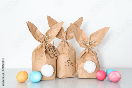 Paper bags bunny with Easter eggs on light background