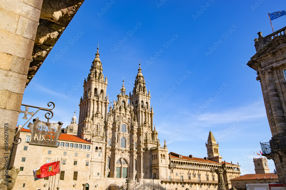 Cathedral of Santiago de Compostela facade with institutional flags  in Obradoiro square and  blue sky