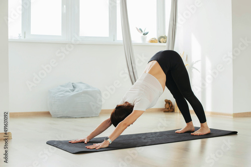 A young girl is doing yoga on the floor in the studio, hall.