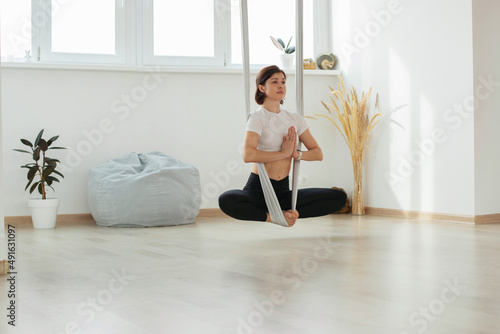 A young brunette girl does yoga, meditates on the floor in the studio, hall.