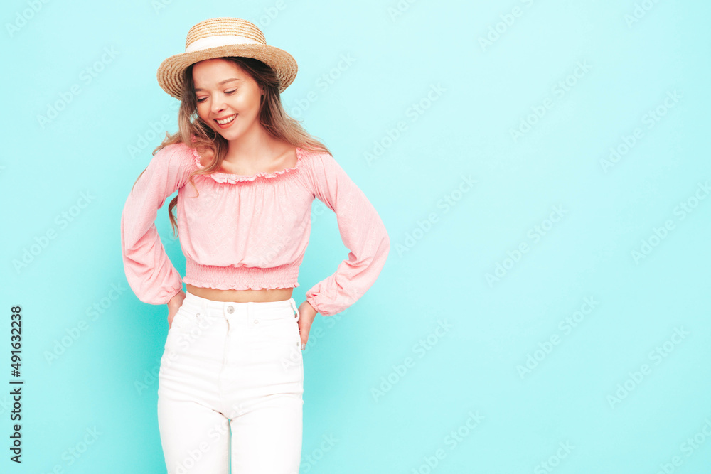 Young beautiful smiling female in trendy summer clothes. carefree woman posing near blue wall in studio. Positive brunette model having fun. Cheerful and happy. In hat Young beautiful smiling female in trendy summer clothes. carefree woman posing near blue wall in studio. Positive brunette model having fun. Cheerful and happy. In hat