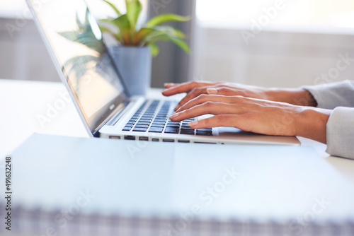 Photos A young woman's hands typing on a laptop in the office