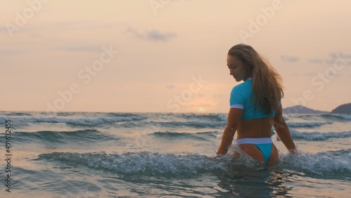 SLOW MOTION GLOW MIST DARK SILHOUETTE CINEMATIC VIEW: Sexy hot woman standing on water sea. Girl stand in turquoise swimsuit. Freedom paradise holiday vacation summer beach, seaside landscape concept