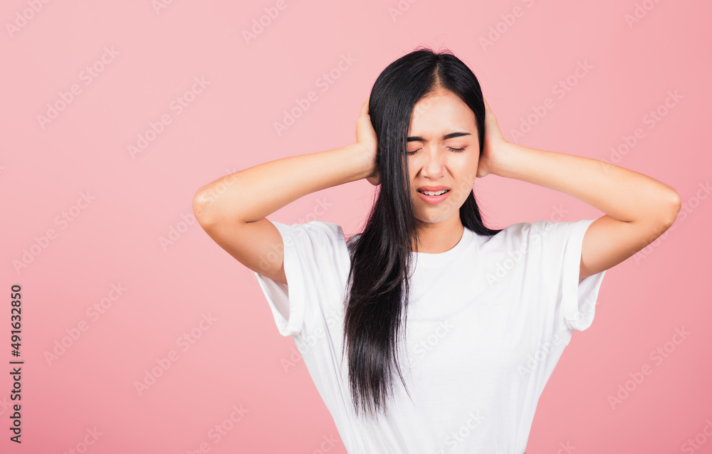 Asian portrait beautiful cute young woman have closed ears with hand palms and close eyes, studio shot isolated on pink background, Thai female covers ears for loud noise with copy space