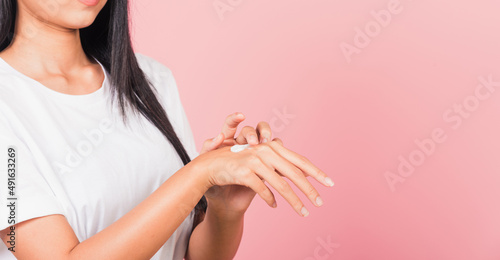 Portrait of Asian beautiful young woman applying lotion cosmetic moisturizer cream on her behind the palm skin back hand, studio shot isolated on pink background, Hygiene skin body care concept