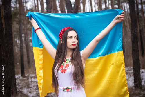 young Ukrainian girl, in traditional Ukrainian dress, embroidery, with the flag of Ukraine in her hands, beads and a wreath on her head, portrait