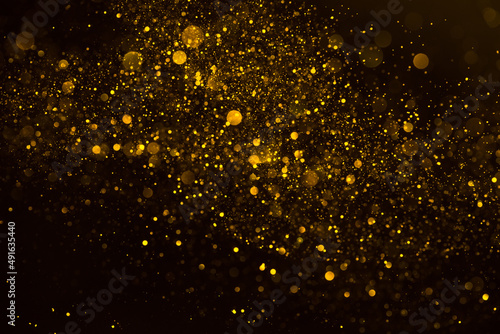 Golden shimmering glitter particles lights abstract background