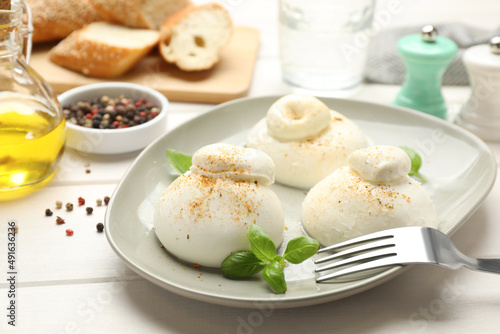 Delicious burrata cheese with basil on white wooden table, closeup