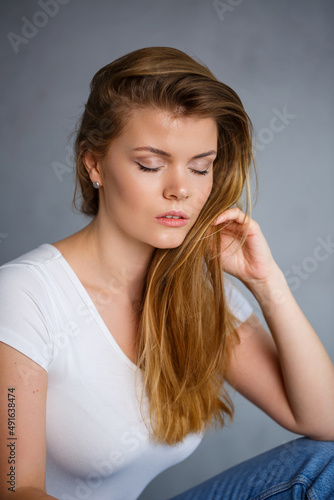Portrait of a young beautiful woman with blond hair of European appearance. Dressed in a white T-shirt. Emotional photo of a person