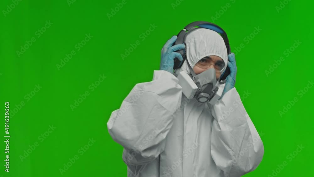 Man in white chemical protection suite wearing respirator and headphones. Man in white chemical protection suite wearing respirator and headphones.