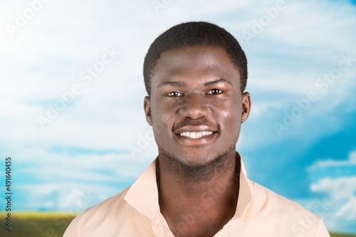 Happy young man smiling in camera on the outdoor background