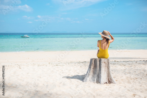 Obraz na plátně Woman tourist in yellow swimsuit and hat, solo traveller looking beautiful sea view at bamboo island on Phi Phi don island, Krabi, Thailand