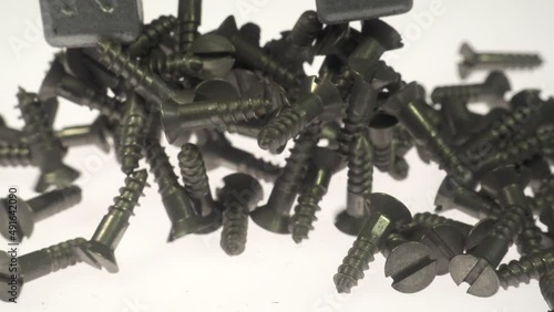 Magnetism, magnetic field and magnetic attraction. A strong horseshoe magnet picking up small steel wood screws.