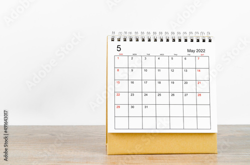 May 2022 desk calendar with plant on wooden table.