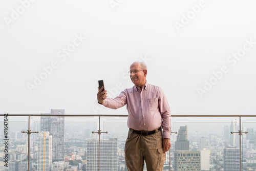 Senior man usingn mobile phone at rooftop in city photo