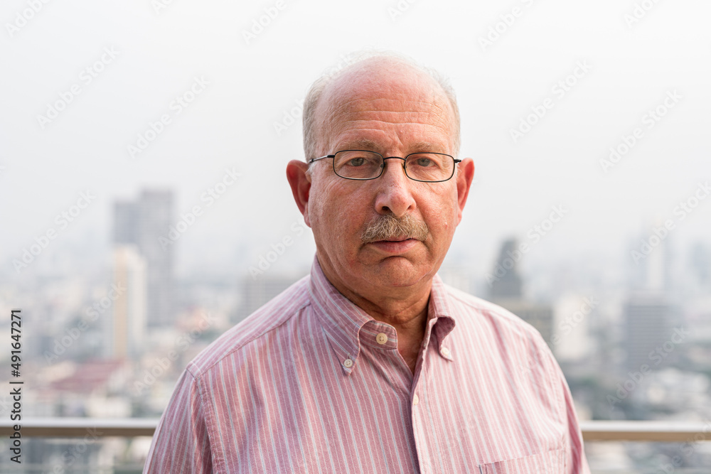 Portrait of senior man looking at camera in city at rooftop Portrait of senior man looking at camera in city at rooftop