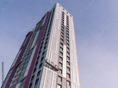 Construction works at height. Finishing construction works of the facade of the building. Suspended facade lift for work on the exterior walls of buildings.