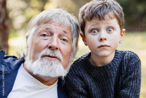 Positive senior grandfather looking at camera and grandson goggle eyes photo