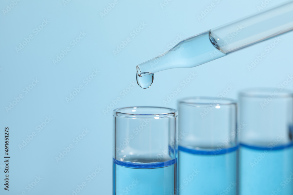 Dripping reagent into test tube on light blue background, closeup. Laboratory analysis Dripping reagent into test tube on light blue background, closeup. Laboratory analysis
