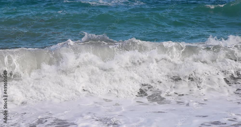 Closeup of breaking wave in the blue ocean with white seaspray in slow motion
