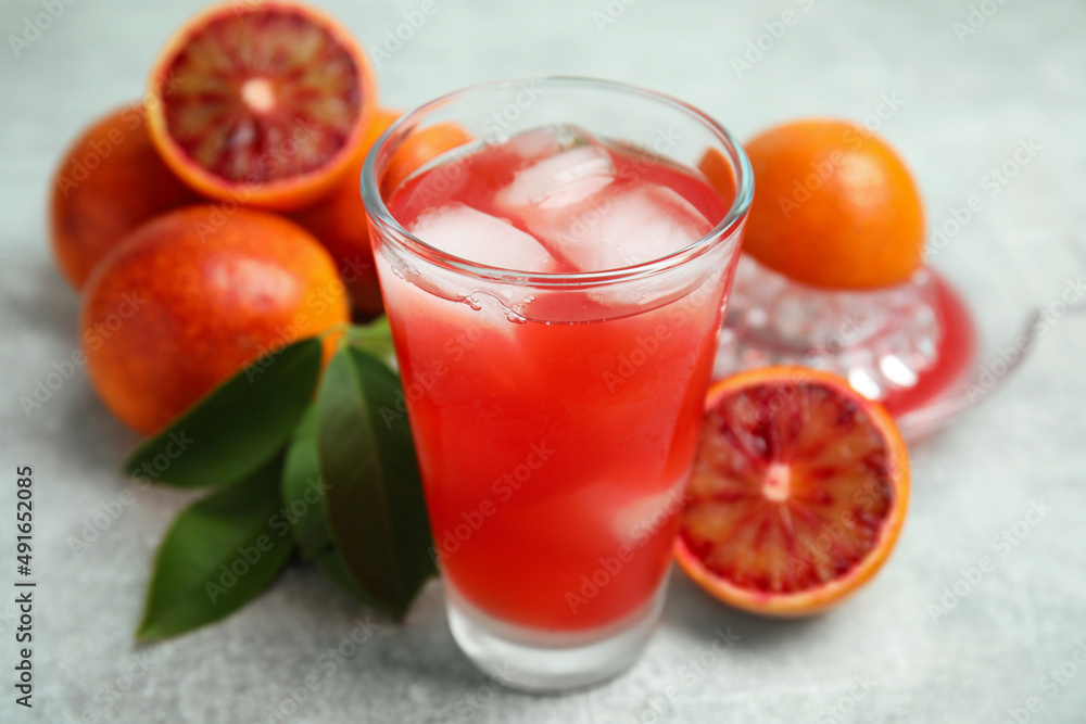 Tasty sicilian orange juice with ice cubes in glass and fruits on light grey table, closeup Tasty sicilian orange juice with ice cubes in glass and fruits on light grey table, closeup