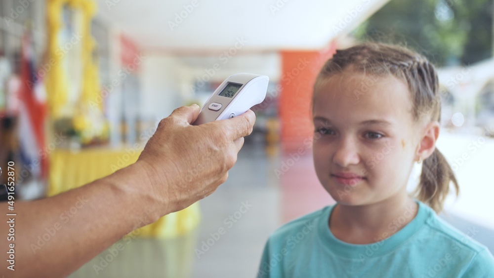 Temperature check at a supermarket of little girl, grocery store with