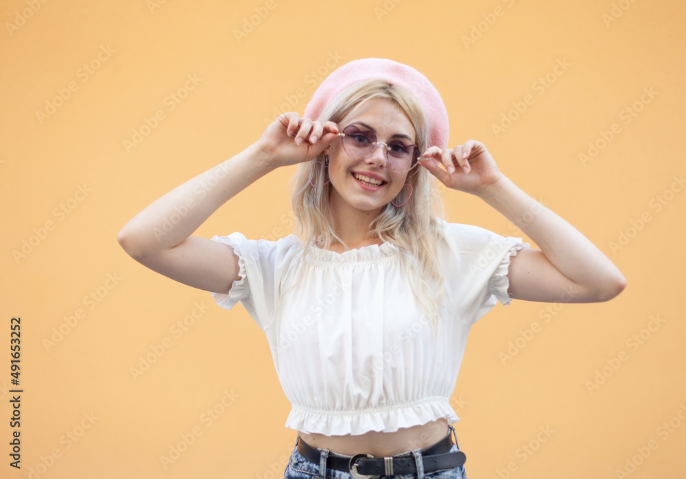 Emotional smiling girl in a beret and sunglasses having fun on yellow background. Portrait of cool hipster woman in trendy outfit. Lifestyle Emotional smiling girl in a beret and sunglasses having fun on yellow background. Portrait of cool hipster woman in trendy outfit. Lifestyle