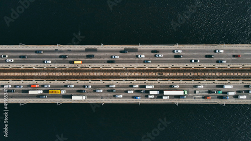 Aerial top view of cars and subway passing the bridge over the river in the city